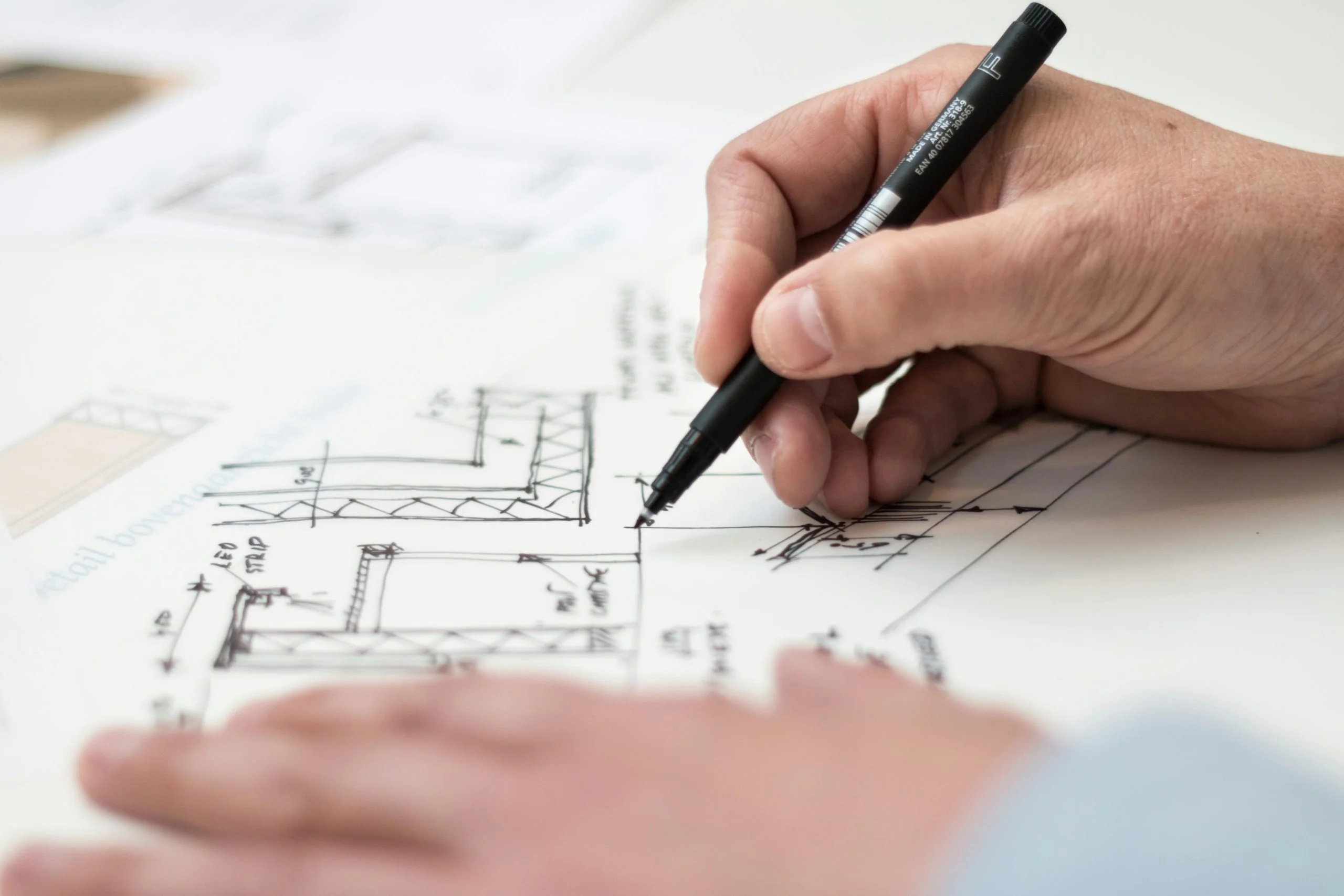 Architect reviewing detailed technical drawings for a UK home extension — elevations and floor plans spread across a desk